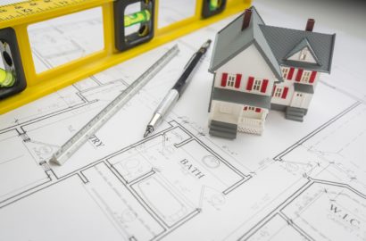 Model Home, Construction Level, Engineer Pencil and Ruler Resting on Custom House Plans.